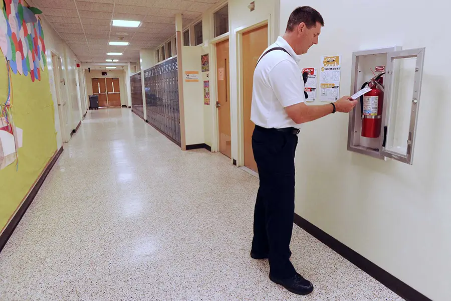 fire sprinkler employee inspecting extinguisher at school