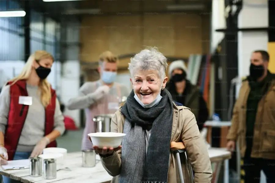 homeless woman getting served a bowl of food